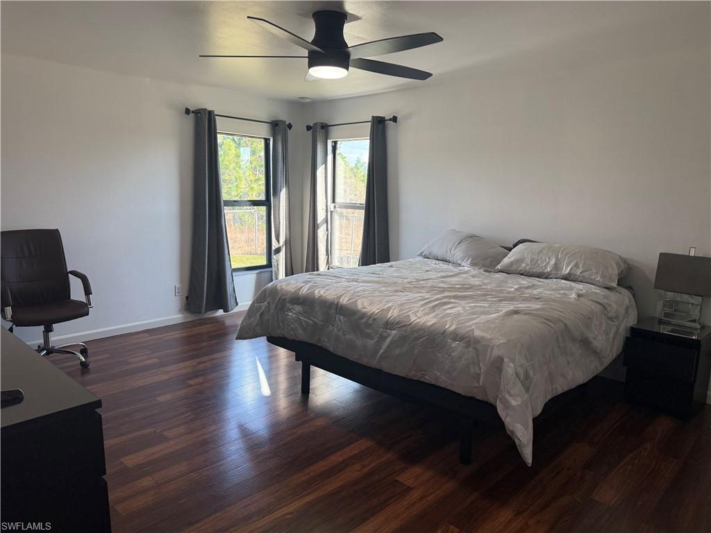 Master bedroom featuring dark laminate wood-type flooring and ceiling fan, two windows offering plenty of natural light.