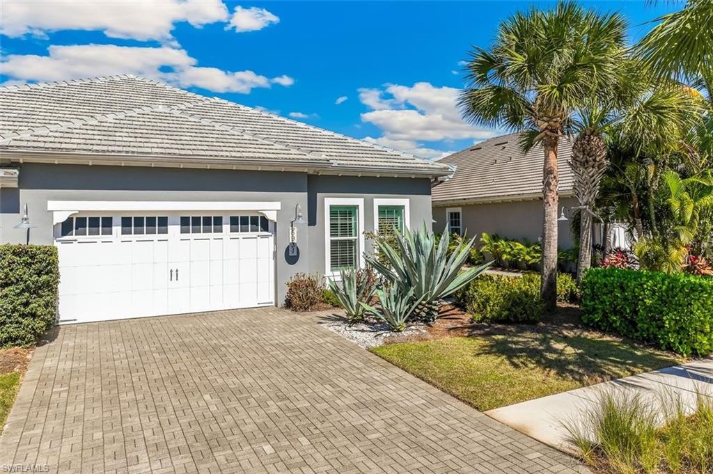 View of front of property with stucco siding, a tiled roof, decorative driveway, and a garage
