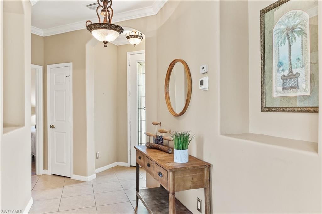 Foyer featuring light tile patterned floors and ornamental molding