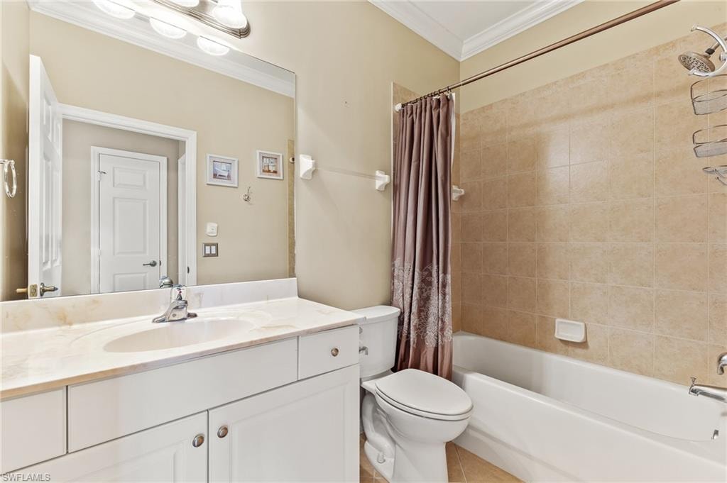 Full bath featuring ornamental molding, shower / bathtub combination with curtain, vanity, and light tile patterned floors
