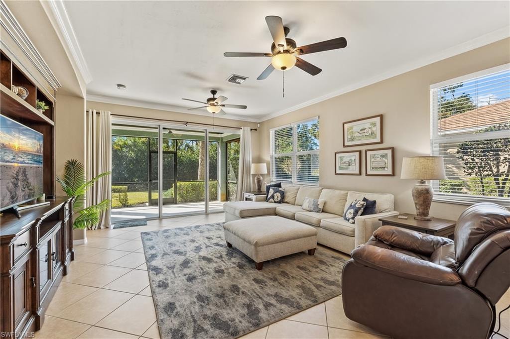 Living room with crown molding, light tile patterned floors, a ceiling fan, and healthy amount of natural light