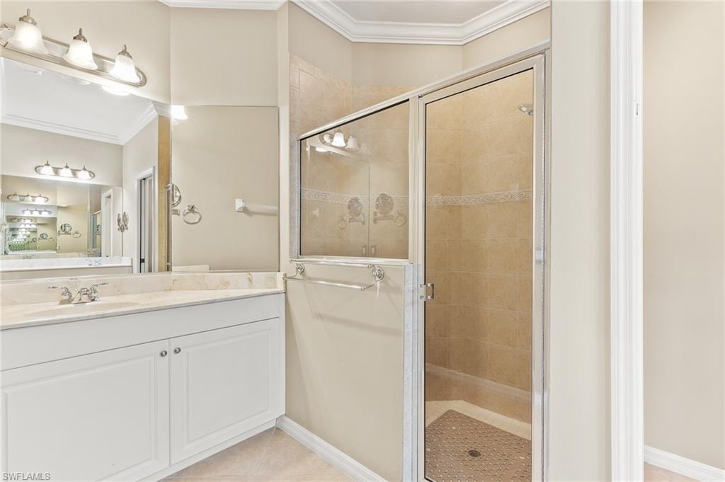 Full bath featuring ornamental molding, a shower stall, vanity, and light tile patterned floors