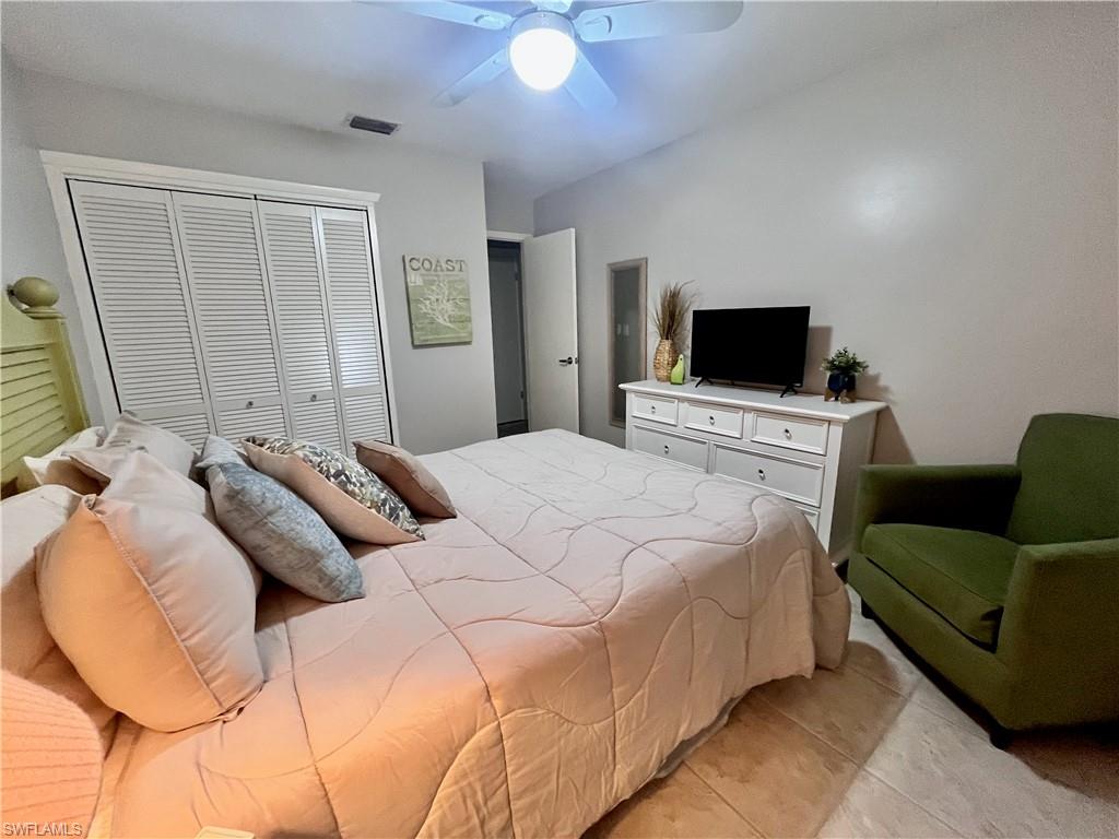 Bedroom with a closet, light tile patterned floors, and ceiling fan