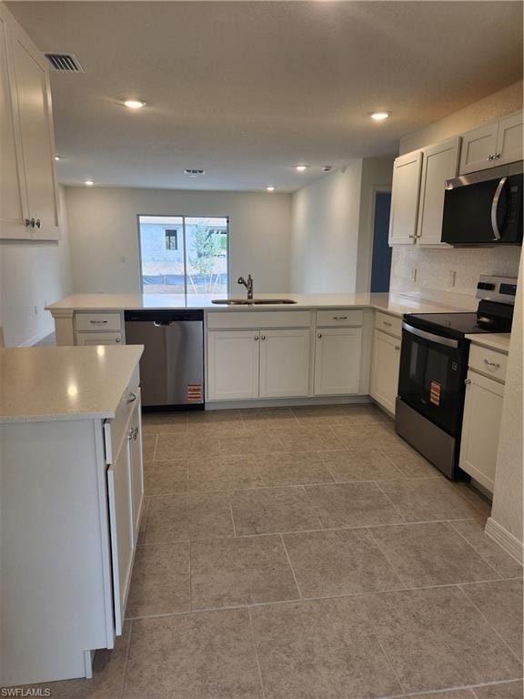 Kitchen featuring range, dishwasher, a peninsula, white cabinets, and recessed lighting