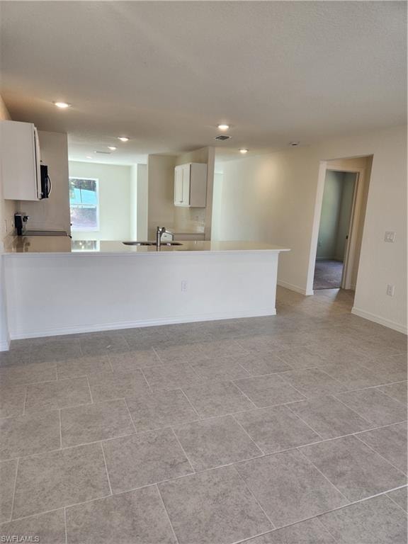 Kitchen with a peninsula, white cabinets, recessed lighting, and range