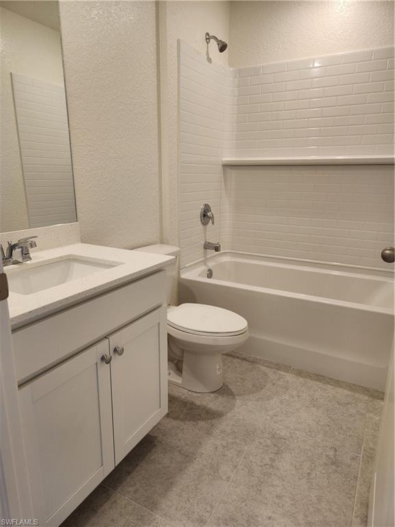Bathroom featuring a textured wall, vanity, tub / shower combination, and light tile patterned floors