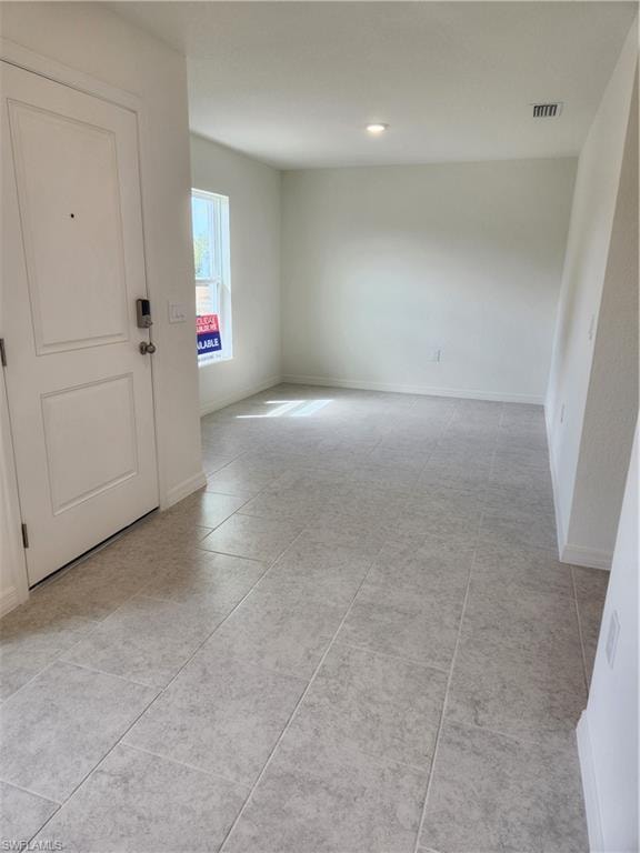 Empty room with baseboards and light tile patterned floors