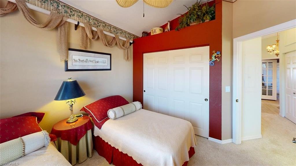 Carpeted bedroom featuring vaulted ceiling and a closet