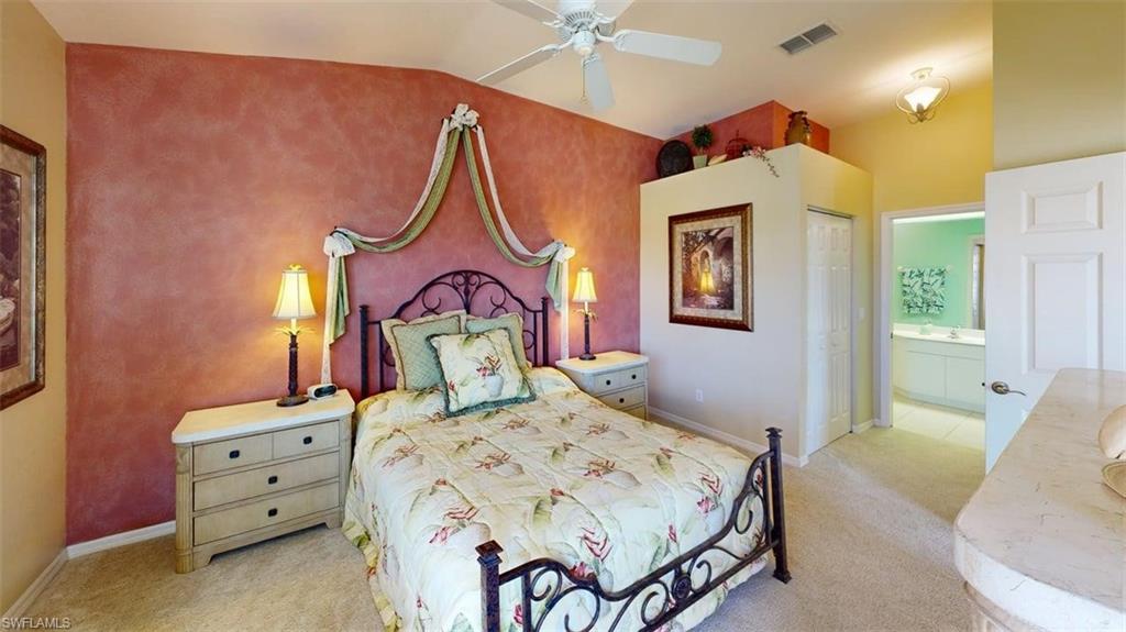 Bedroom featuring light carpet, a closet, ensuite bathroom, a ceiling fan, and lofted ceiling