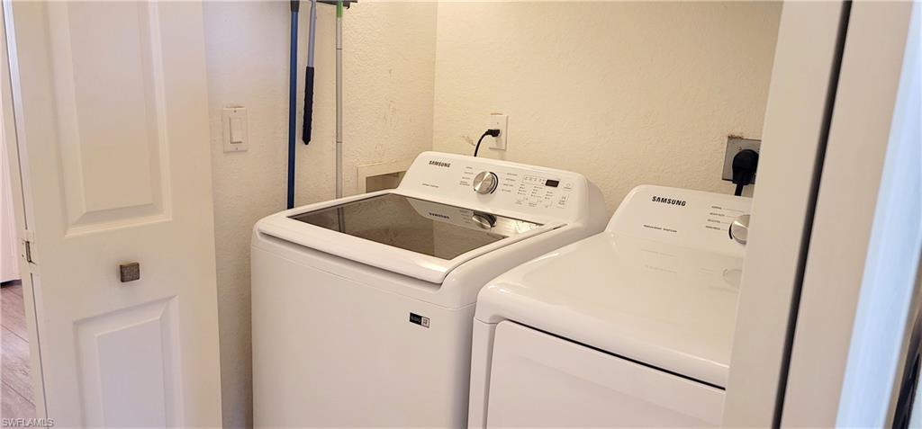 Laundry area with a textured wall and washer and clothes dryer