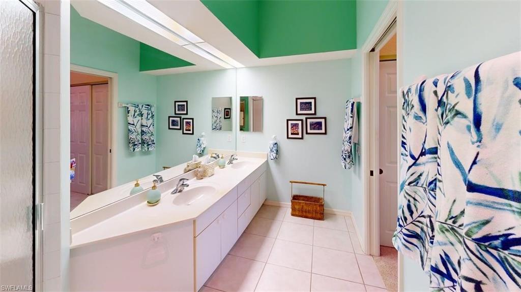 Full bathroom with double vanity, light tile patterned floors, and curtained shower
