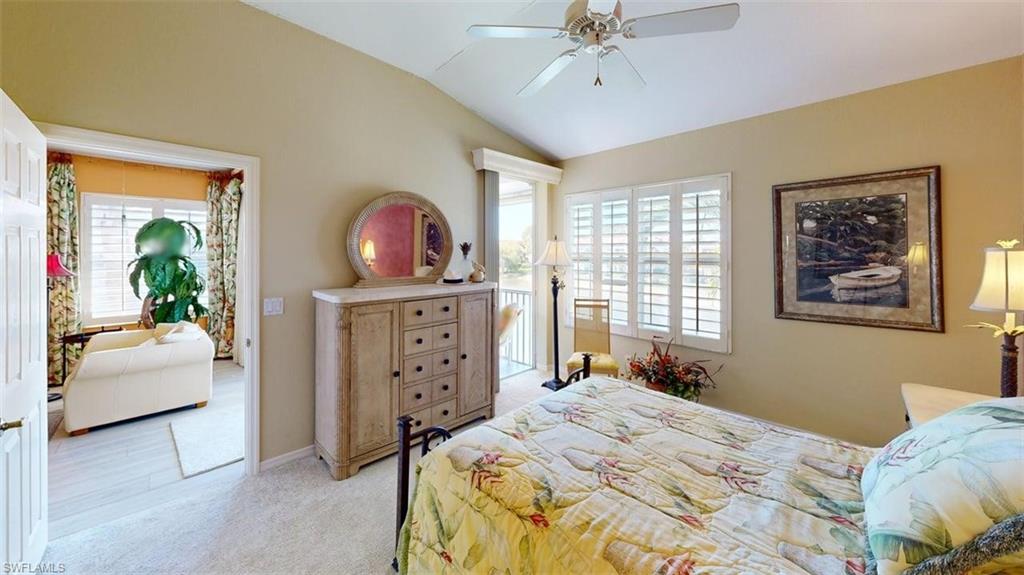 Bedroom featuring access to exterior, lofted ceiling, light colored carpet, and a ceiling fan