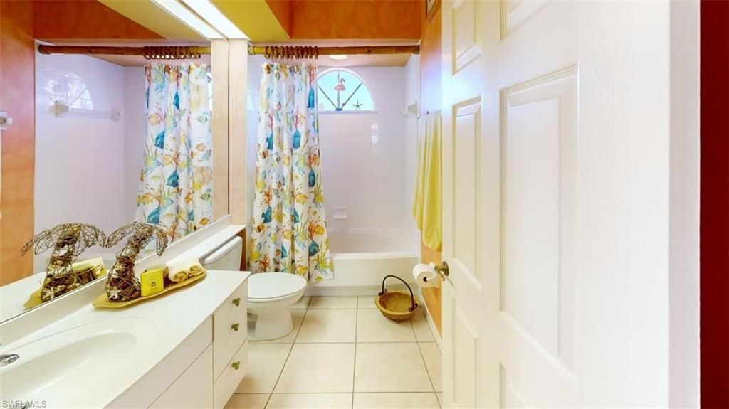 Bathroom with vanity, shower / bath combo with shower curtain, and light tile patterned floors