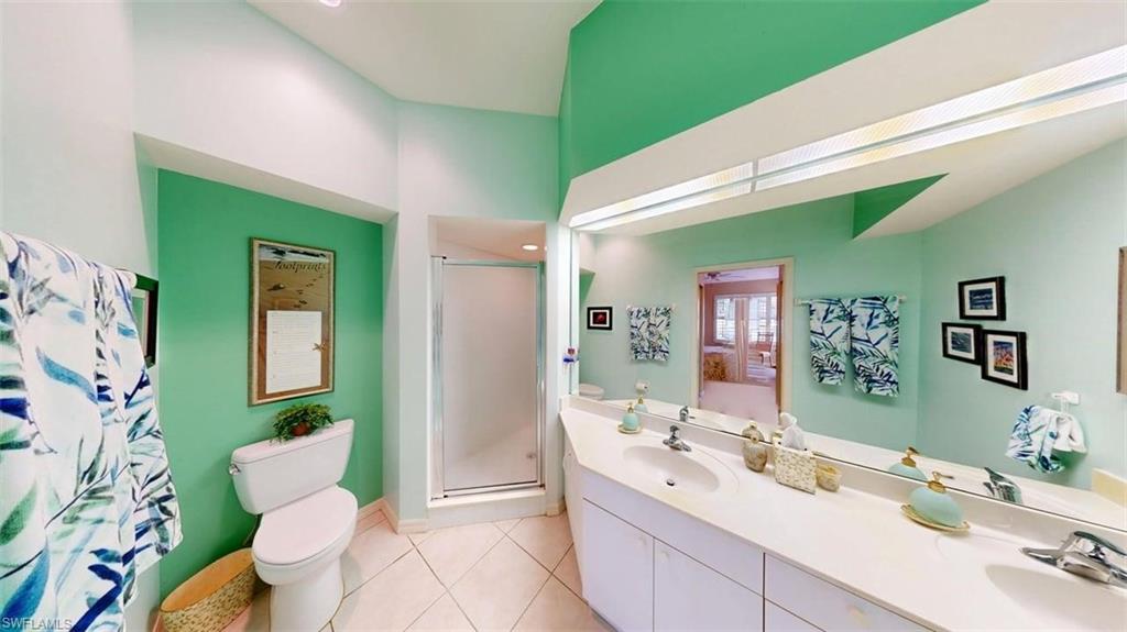 Full bath featuring a stall shower, double vanity, light tile patterned floors, and recessed lighting