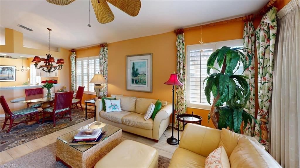 Living room featuring wood finished floors, vaulted ceiling, a ceiling fan, and suspended lighting