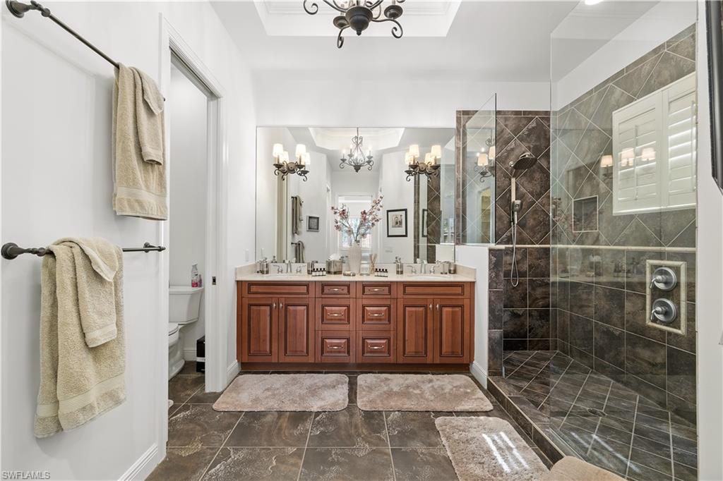 Bathroom featuring walk in shower, suspended lighting, and double vanity