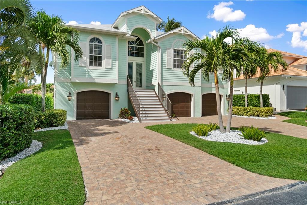 Coastal inspired home with a garage, decorative driveway, and stucco siding