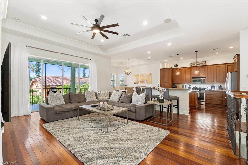 Living room with a ceiling fan, dark wood finished floors, crown molding, recessed lighting, and a raised ceiling