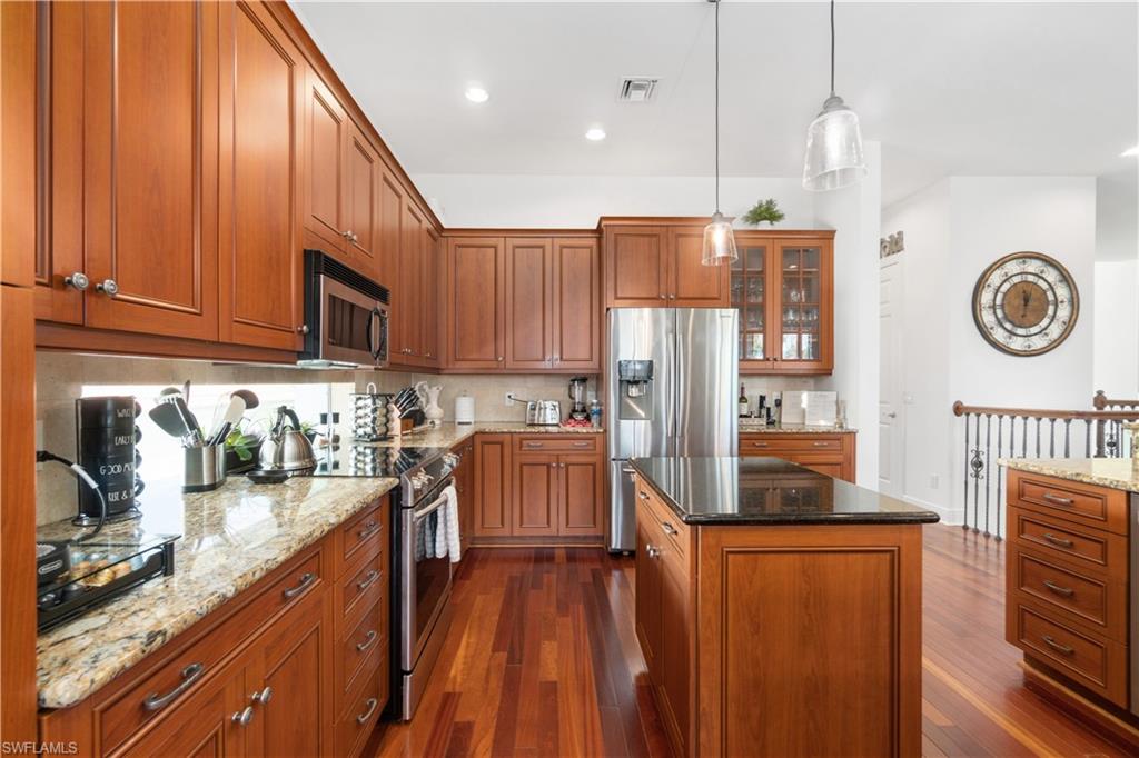 Kitchen featuring dark stone countertops, wood finish cabinets, and stainless steel appliances
