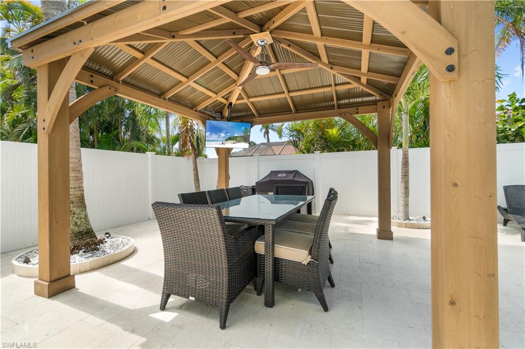 Fenced backyard with a gazebo, outdoor dining area, a patio area, and a grill