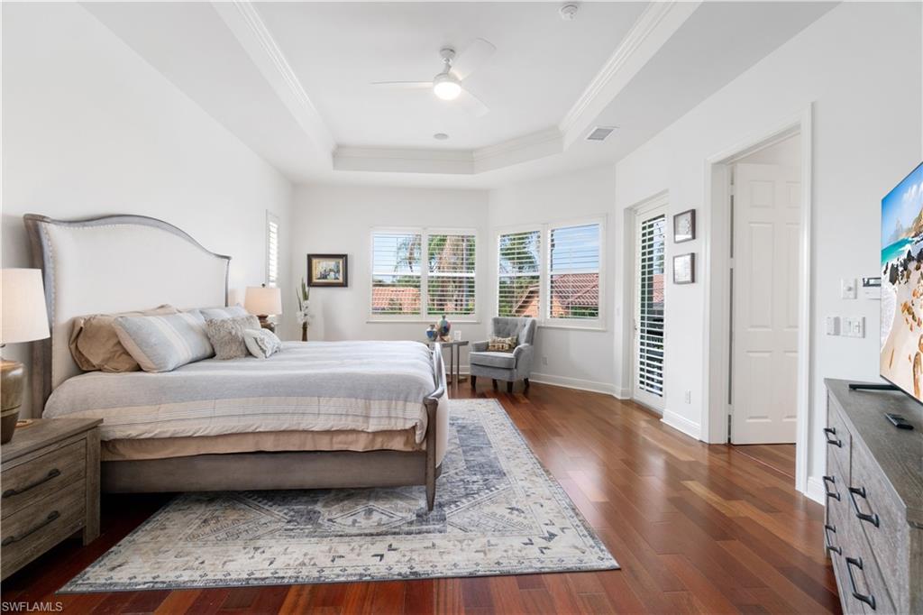 Bedroom featuring dark wood-type flooring, ornamental molding, a ceiling fan, and a raised ceiling