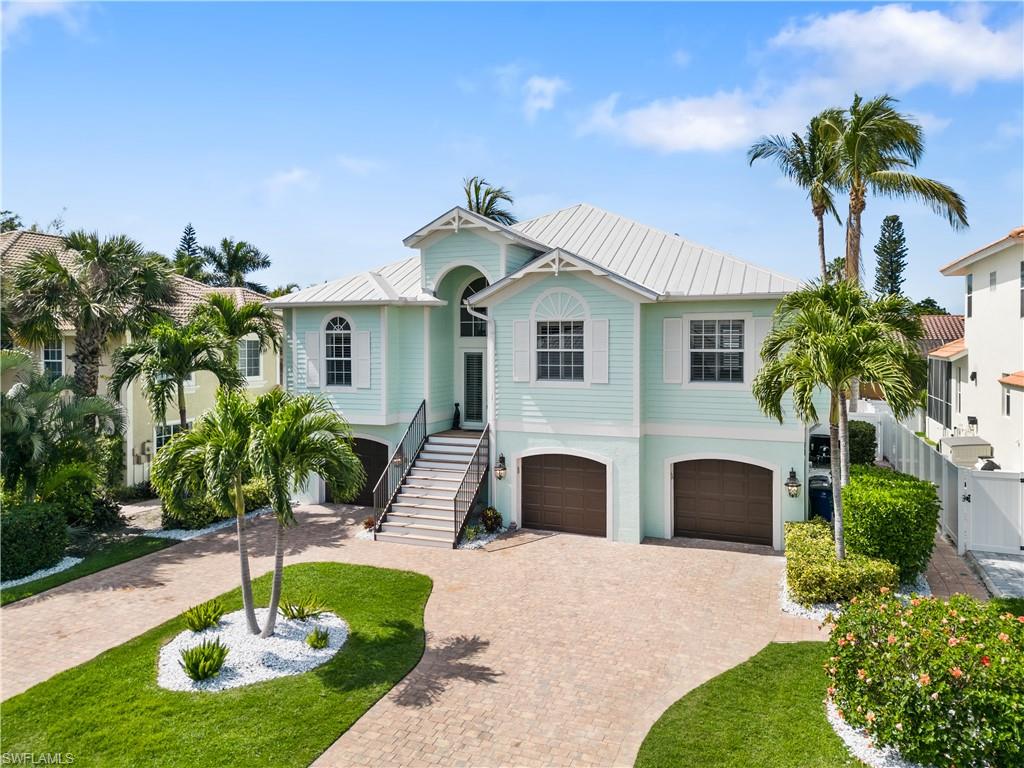Coastal inspired home featuring a standing seam roof, an attached garage, and decorative driveway