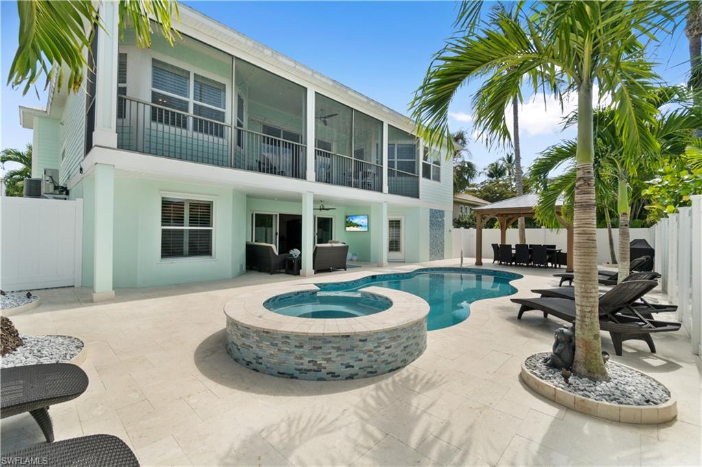 Back of house featuring a patio, a balcony, stucco siding, a fenced backyard, and a pool with connected hot tub