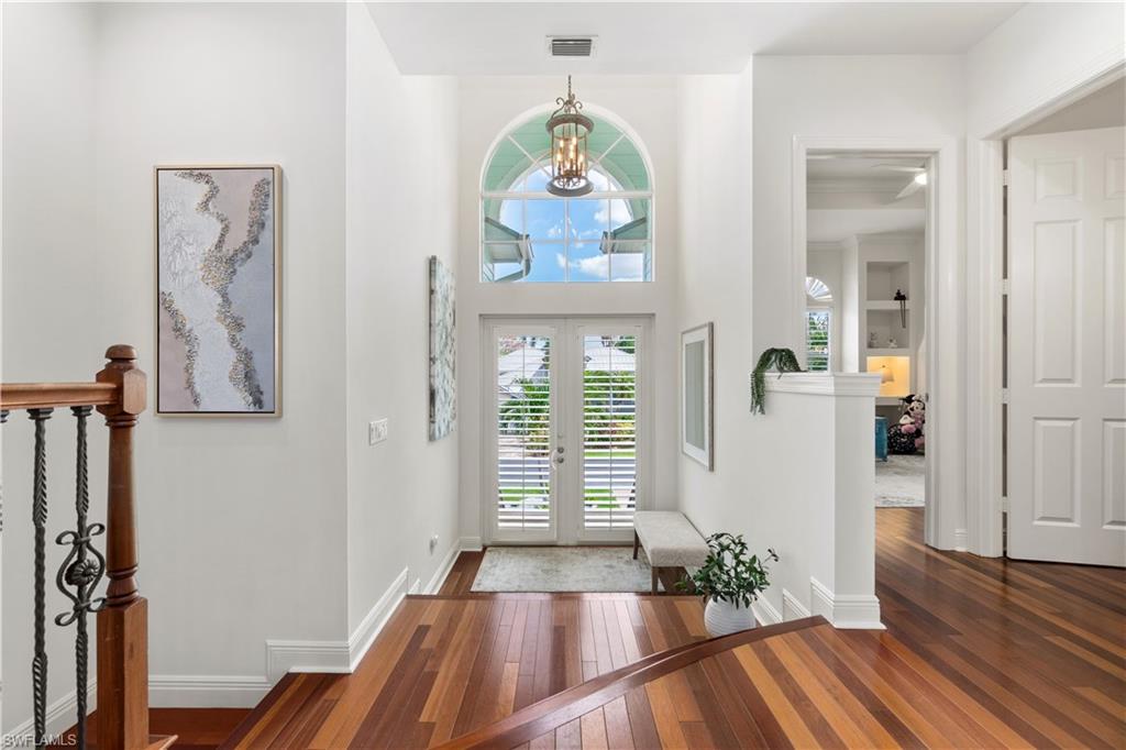 Entryway with dark wood-style flooring, hanging lights, french doors, and a high ceiling