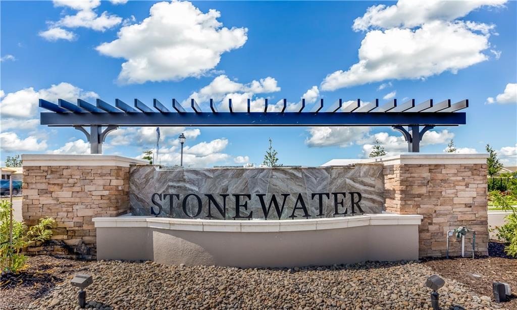 The community entrance features a stone and stucco monument with a pergola-style accent