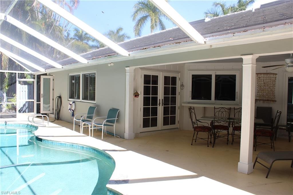 Swimming pool featuring french doors, a patio area, a sunroom, glass enclosure, and outdoor dining area