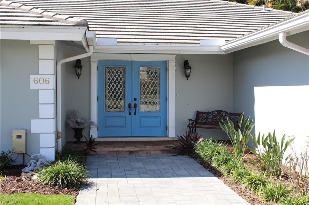 Doorway to property with french doors, a tile roof, and stucco siding