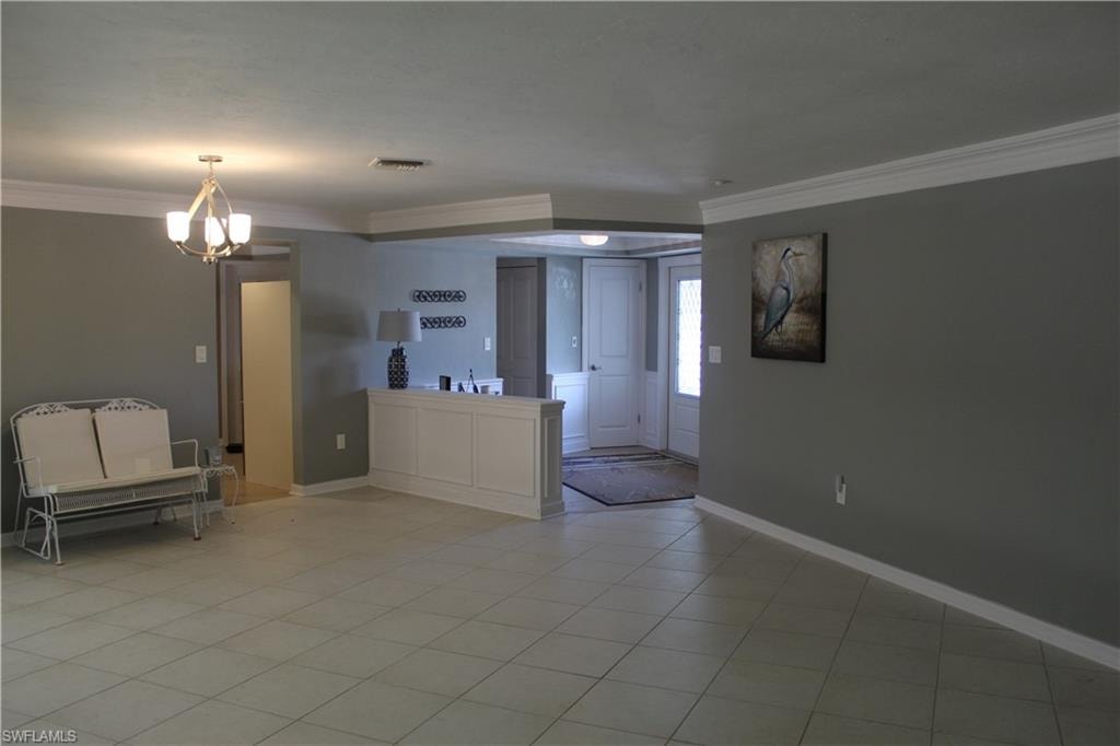 Unfurnished living room featuring ornamental molding, hanging lights, and light tile patterned flooring