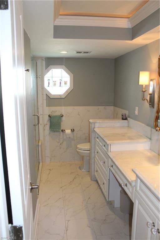 Bathroom with vanity, a marble finish shower, light marble finish flooring, ornamental molding, and wainscoting