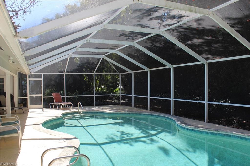 Swimming pool featuring a lanai, a sunroom, and a patio