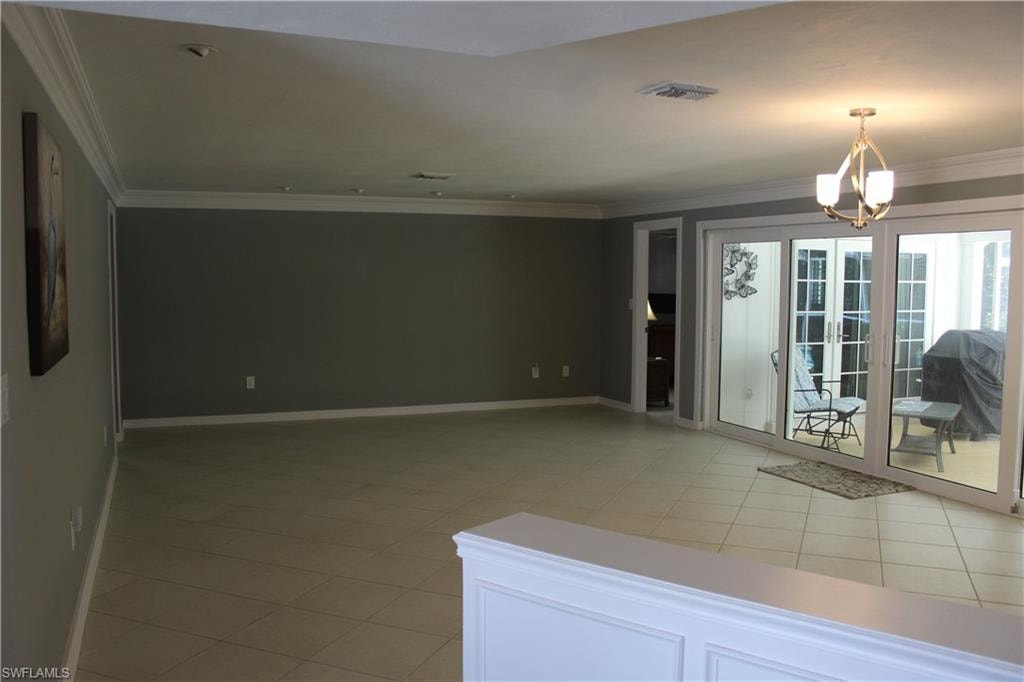 Unfurnished room with ornamental molding, light tile patterned floors, and hanging lights