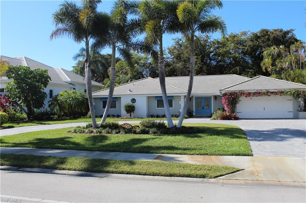 Ranch-style house with driveway, a front lawn, french doors, and a garage