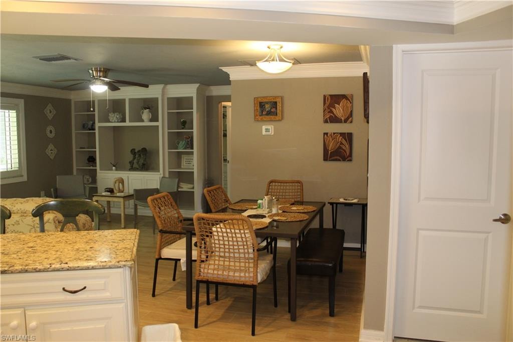 Dining area with crown molding, light wood finished floors, and a ceiling fan