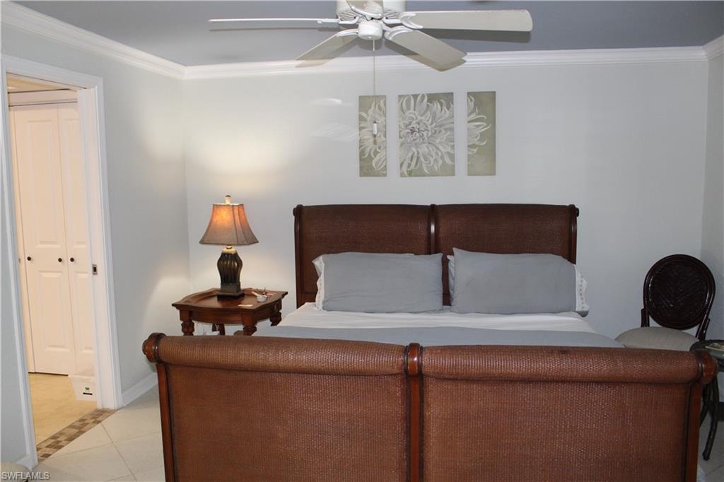 Tiled bedroom featuring ornamental molding, a closet, and a ceiling fan