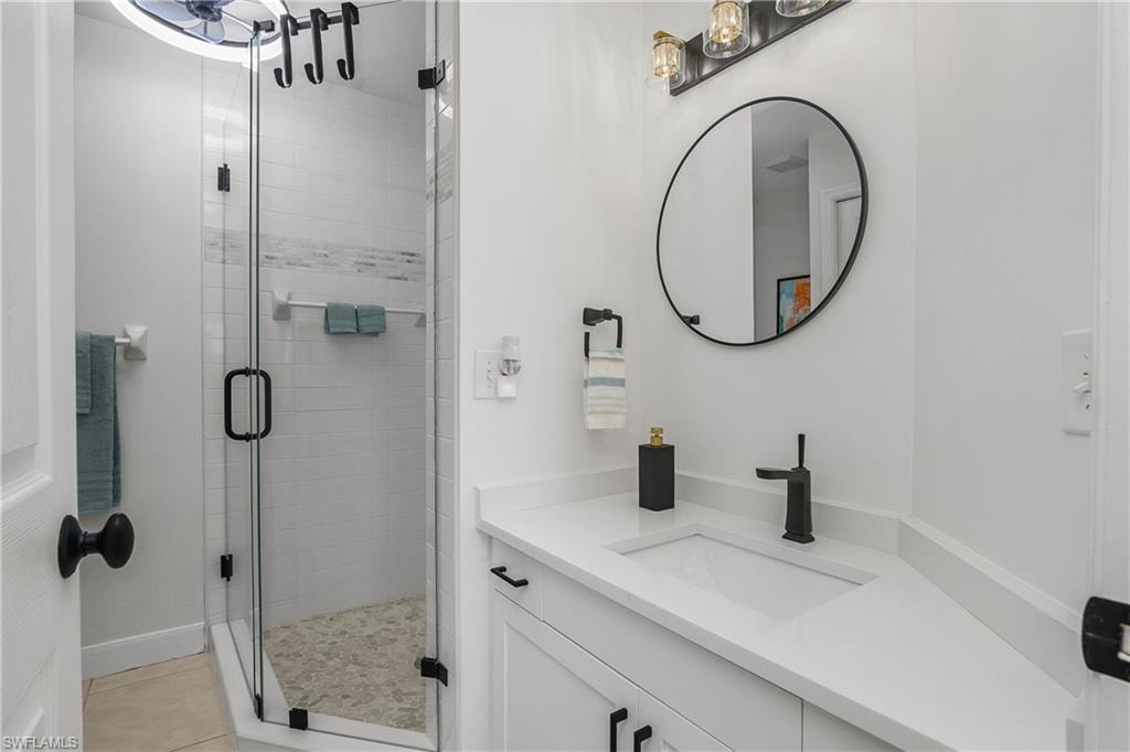 Full bath with a stall shower, vanity, and light tile patterned flooring