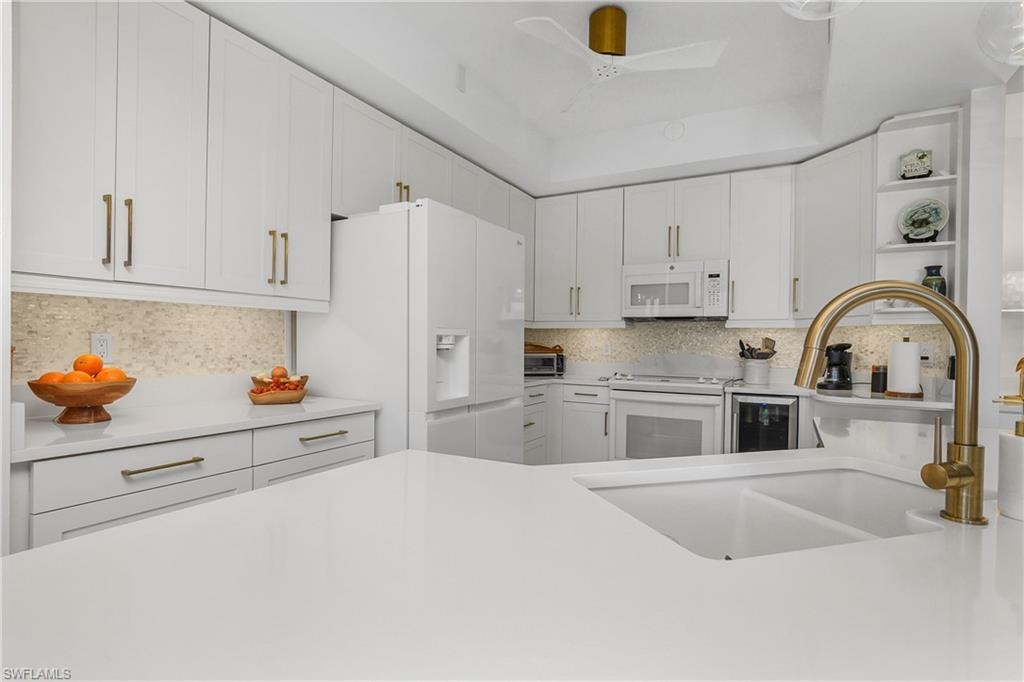 Kitchen with open shelves, white cabinets, white appliances, ceiling fan, and light stone counters