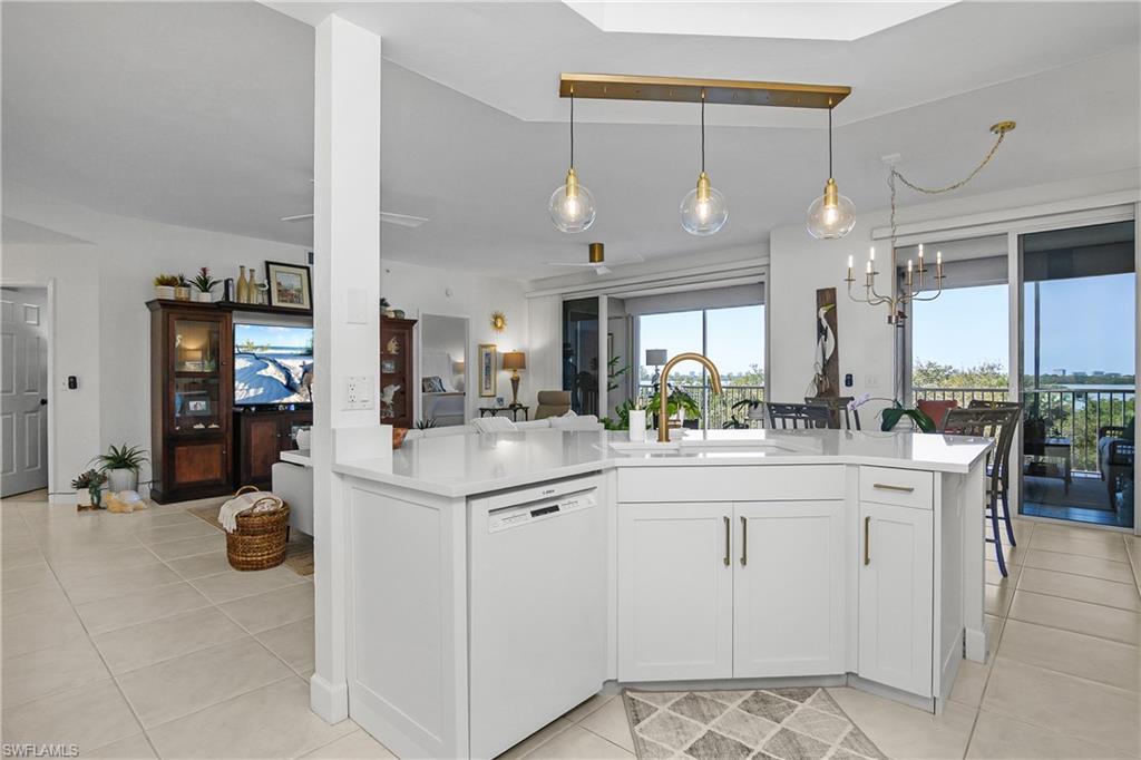Kitchen featuring white dishwasher, white cabinetry, open floor plan, a chandelier, and light tile patterned flooring