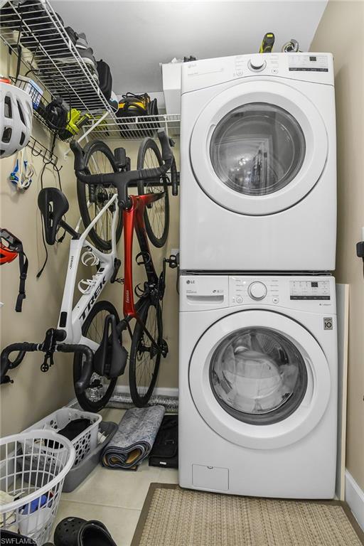 Laundry room featuring stacked washer and clothes dryer and light tile patterned flooring