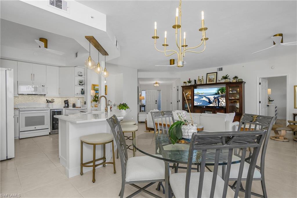 Dining space featuring a ceiling fan, wine cooler, and light tile patterned flooring