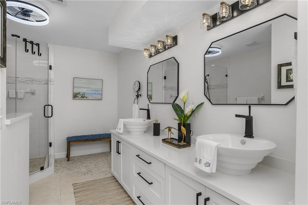 Bathroom with a shower stall, double vanity, and light tile patterned flooring