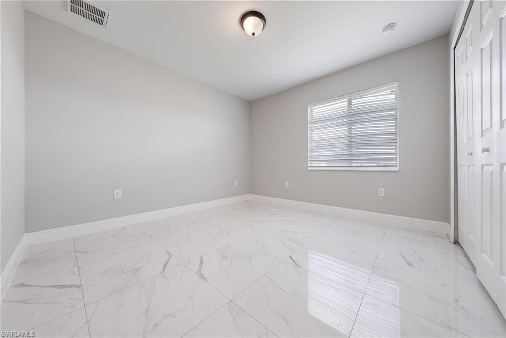 Unfurnished bedroom with light marble finish flooring and a closet