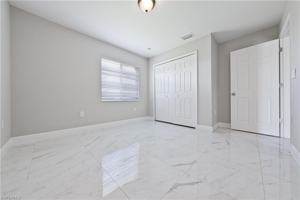 Unfurnished bedroom with light marble finish flooring and a closet