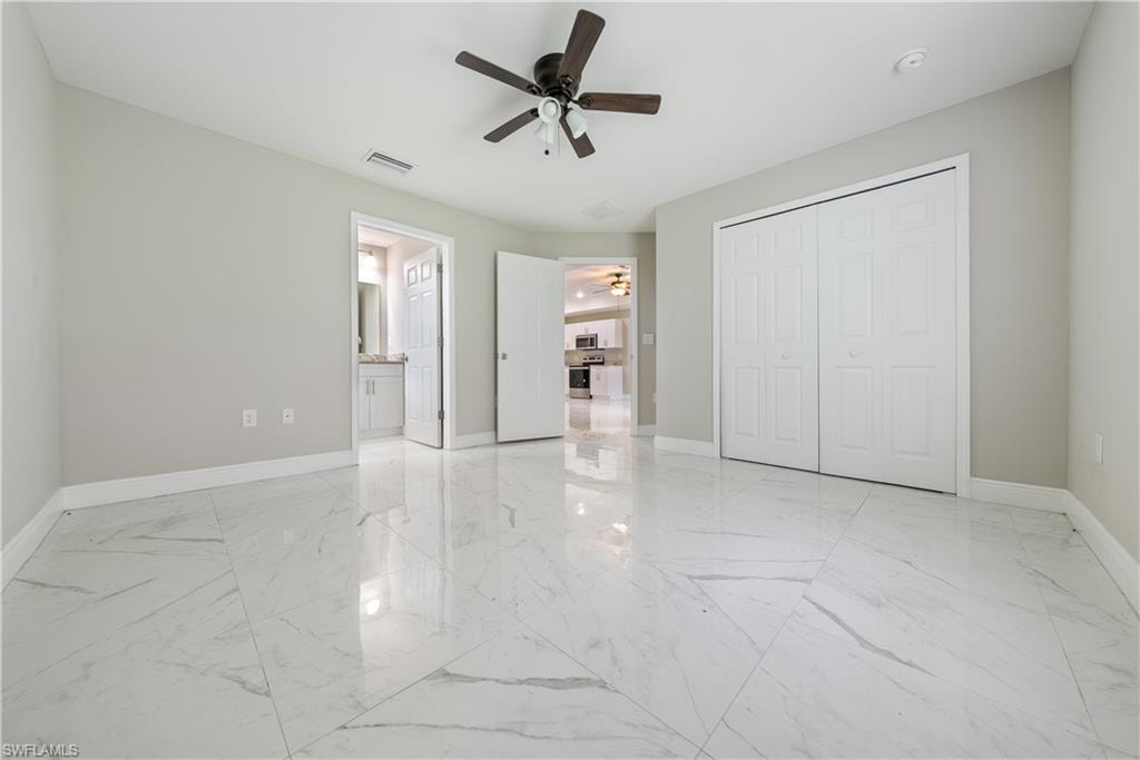 Unfurnished bedroom with ceiling fan, light marble finish flooring, and a closet