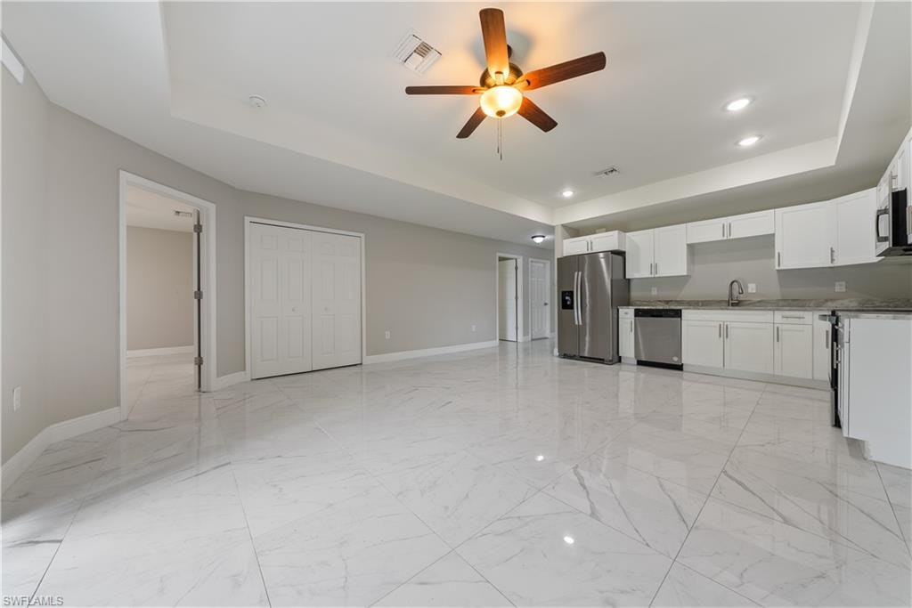 Kitchen featuring a tray ceiling, white cabinets, ceiling fan, stainless steel appliances, and recessed lighting