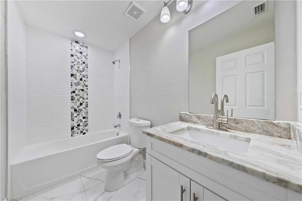 Full bath with vanity, bathtub / shower combination, and light marble finish flooring