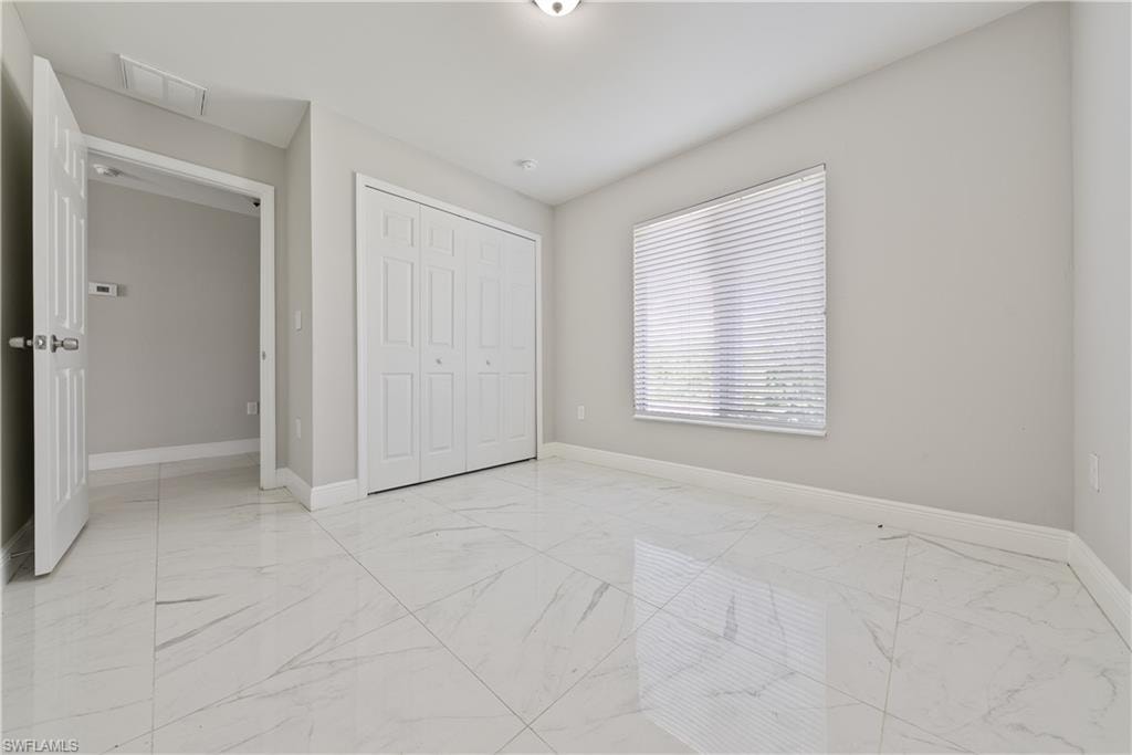 Unfurnished bedroom with light marble finish flooring and a closet